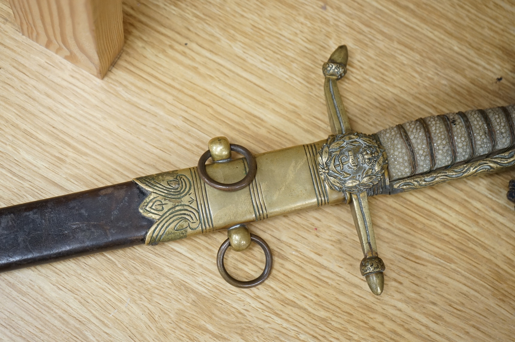 A post 1902 Naval Officer’s Dirk, the regulation blade with crowned fouled anchor, regulation hilt with remains of bullion dress knot in its leather scabbard with brass mounts, locket engraved with owners initials; RSA